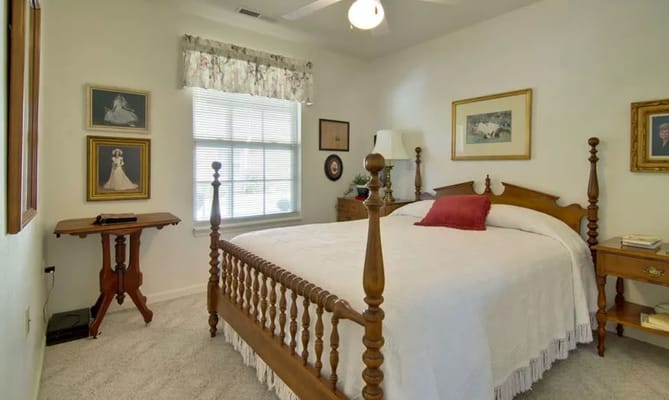 A cozy bedroom featuring a wooden bed, bedside tables, and decorative paintings.
