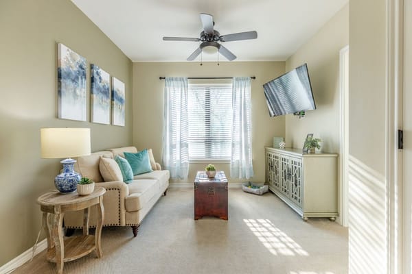 A comfortable living room featuring a couch, decorative lamp, and a television.