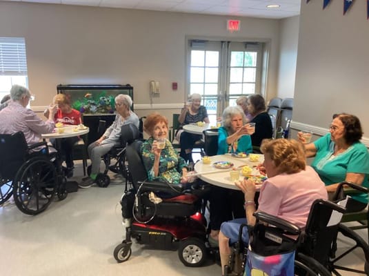 Seniors gathered around tables enjoying drinks and snacks.