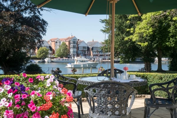 Outdoor patio with flowers, table set near the river