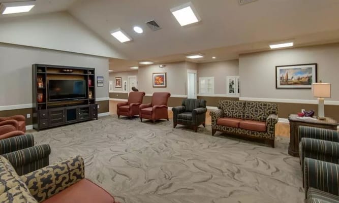 Lounge area with seating and a television in the senior living facility.