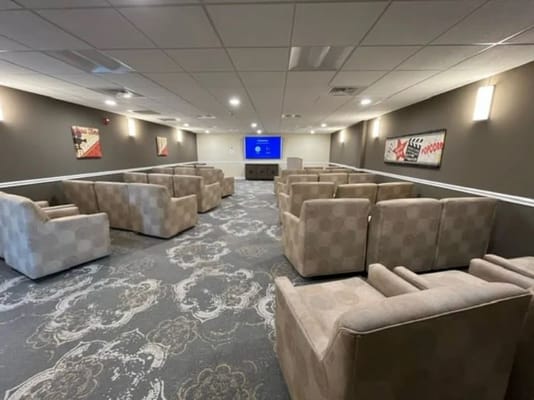 Seating area with fabric armchairs and a large screen in the background