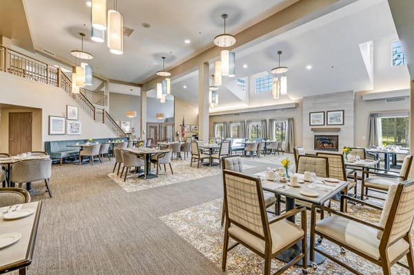Spacious dining area featuring tables set for meals and large windows.