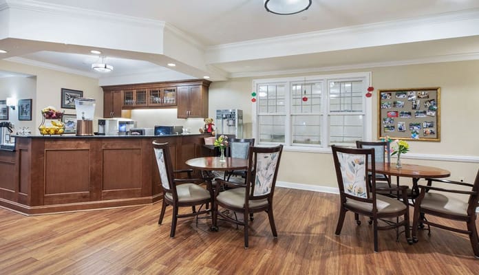 Lounge area with tables and kitchen in The Bradford Senior Living