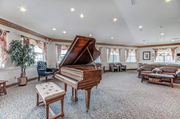 A lounge area featuring a grand piano, seating, and large windows