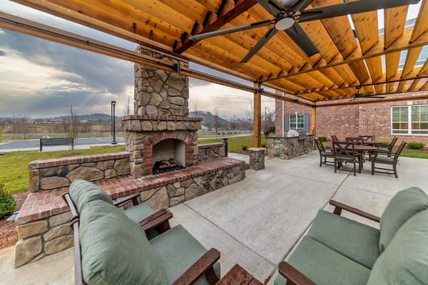 Outdoor seating area with a stone fireplace and dining table.