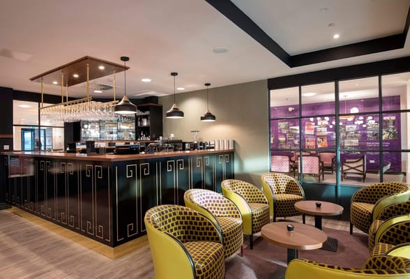 Chic lounge bar with yellow and patterned chairs and a modern bar setup.
