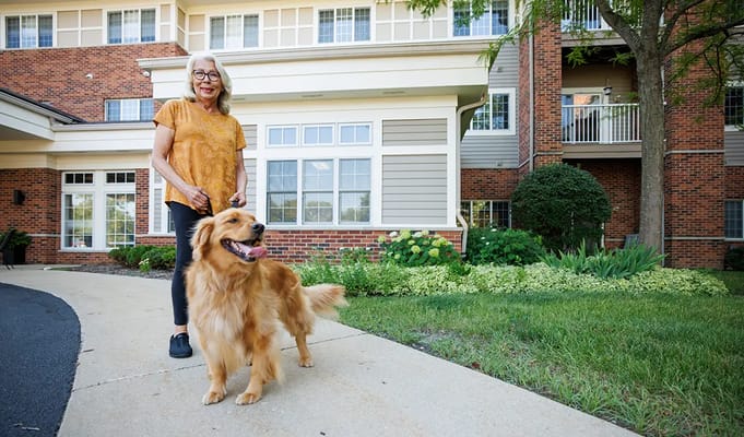 Resident with a golden retriever in front of the building