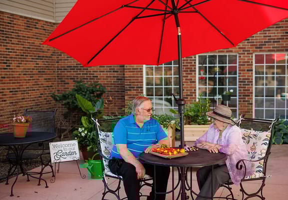 Two seniors enjoying fruit at a garden table