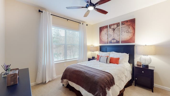 A well-decorated bedroom with a bed, lamp, and window