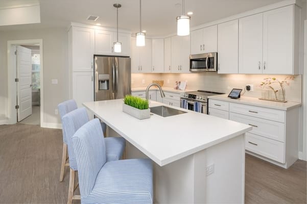 Bright, modern kitchen with white cabinetry and blue chairs