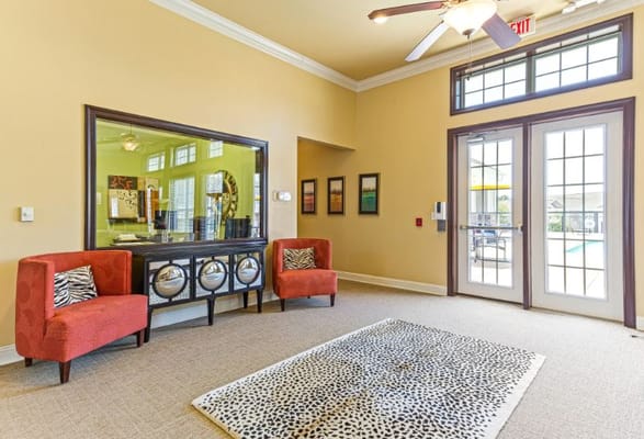 Cozy lobby with red chairs and large mirrors.