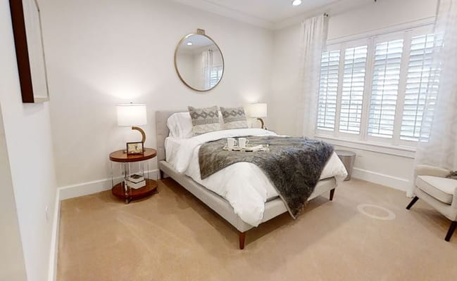 Stylish bedroom featuring a bed with decorative pillows and a mirror