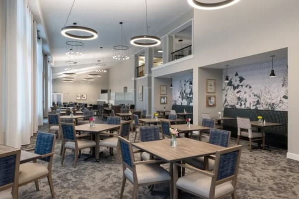 Bright dining area with tables and chairs in The Esther at Riverbend