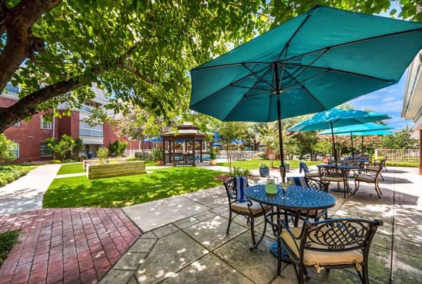 A sunny outdoor patio with tables and umbrellas at The Forum at Lincoln Heights.