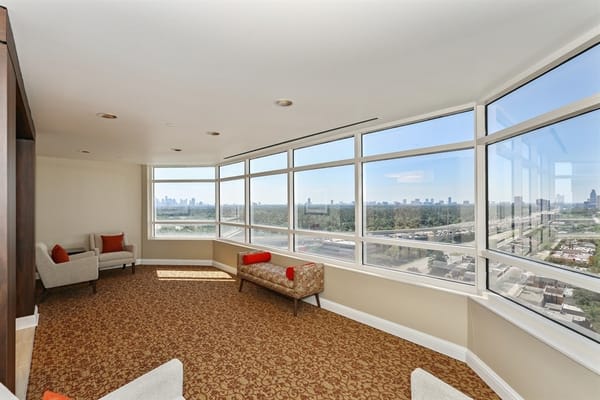 Bright sunroom with seating and large windows showcasing the city skyline.