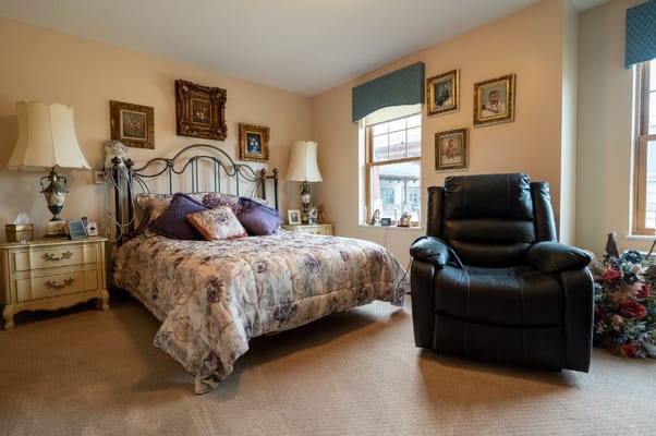 A beautifully decorated bedroom featuring a floral bedspread and a leather recliner.