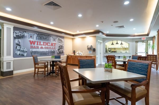 Seating area with tables and chairs in Wildcat Bar & Grill, featuring a mural.