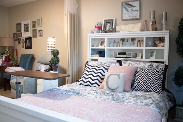 A neatly arranged bedroom featuring a bed with decorative pillows and a bedside table.