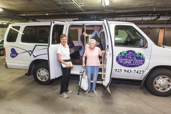Residents and staff by the facility transport van