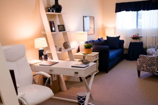 A cozy living room with a desk, comfortable seating, and decorative items.