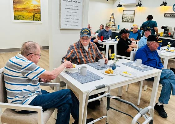 Seniors dining together at tables in a communal setting.
