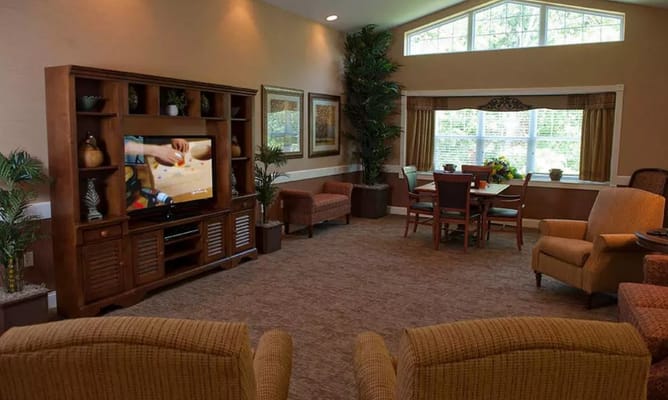Inviting living room with seating and a TV in a senior living facility.