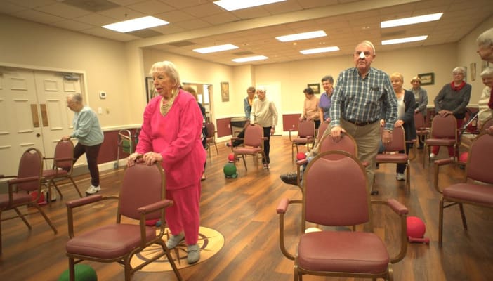 Seniors participating in an exercise class with chairs