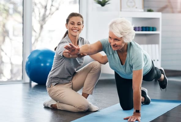 Senior woman engaging in exercise with the help of a trainer