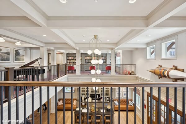 View of the lounge area from an upper level with a piano and bookshelves.