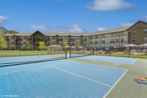 Tennis court with blue surface and residential building in the background