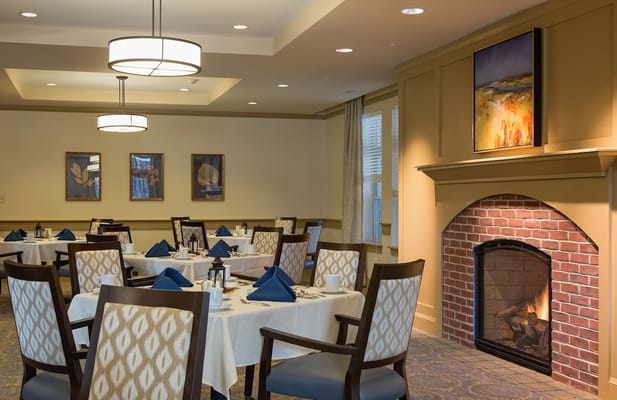 Elegant dining room setup with tables, blue napkins, and a fireplace