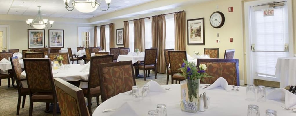 Dining area with tables set for meals in a senior living facility