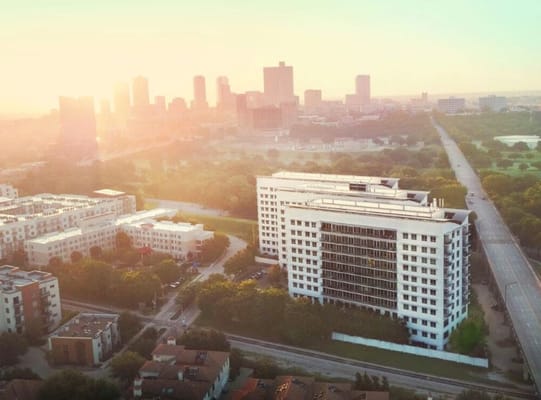 Aerial view of The Stayton at Museum Way building with a sunset backdrop over Fort Worth, TX.