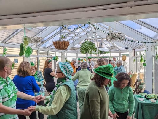 Residents celebrating St. Patrick's Day in a decorated sunroom.