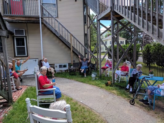 Seniors socializing outside in a garden area with a wooden staircase in the background.