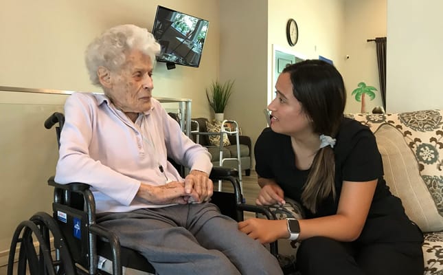 A caregiver speaking with an elderly resident in a cozy setting.