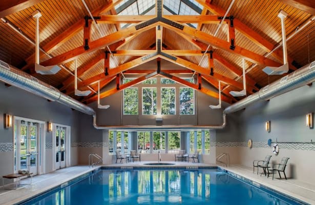 Bright indoor pool with wooden ceiling and seating area
