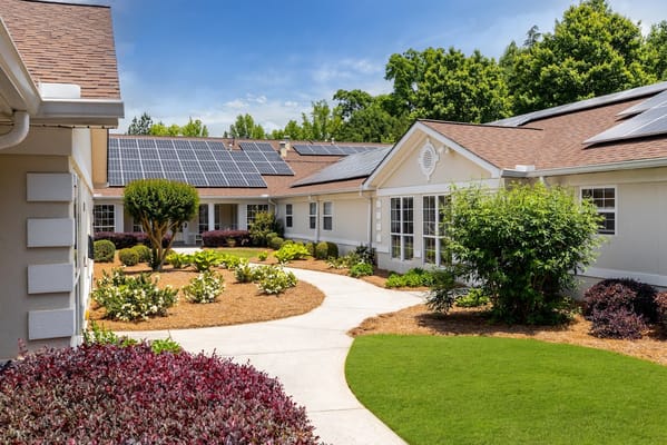 A sunny garden view of The Waterford at Decatur with solar panels on the roof.