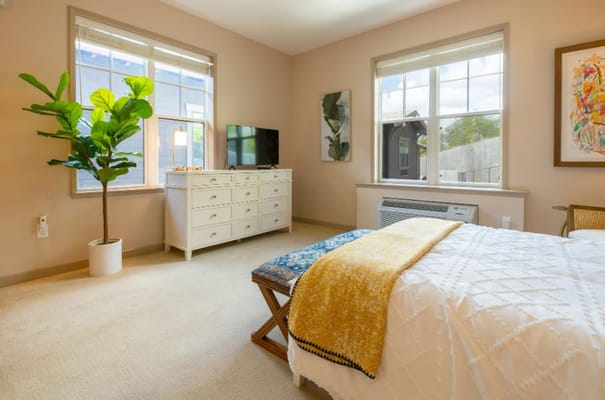 Stylish bedroom with a bed, dresser, and large windows