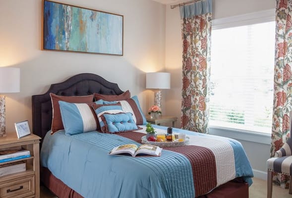 A well-decorated bedroom featuring a bed with colorful bedding and a small table with snacks