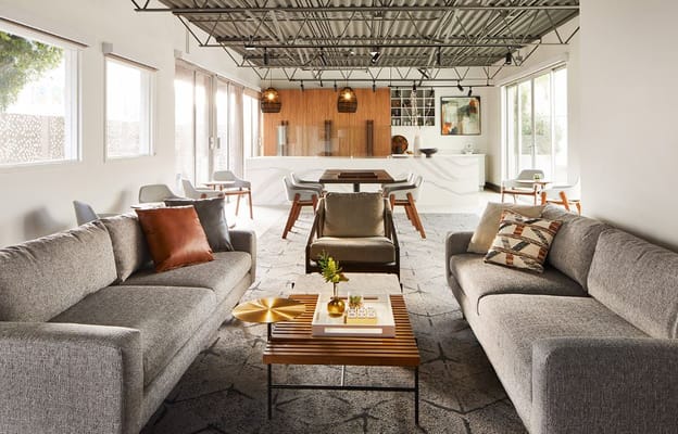 A modern living room with gray sofas, a wooden coffee table, and large windows.
