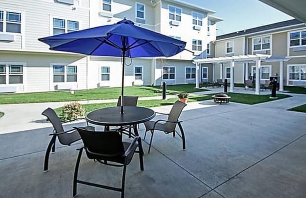Table and chairs under a blue umbrella in the courtyard