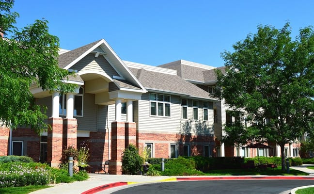 The exterior of The Wexford senior living facility with landscaped gardens.