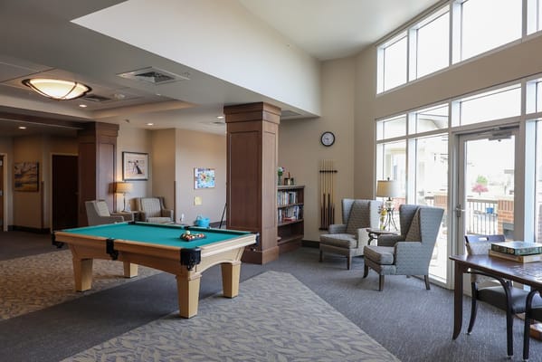 Billiards table in a lounge area with seating and windows