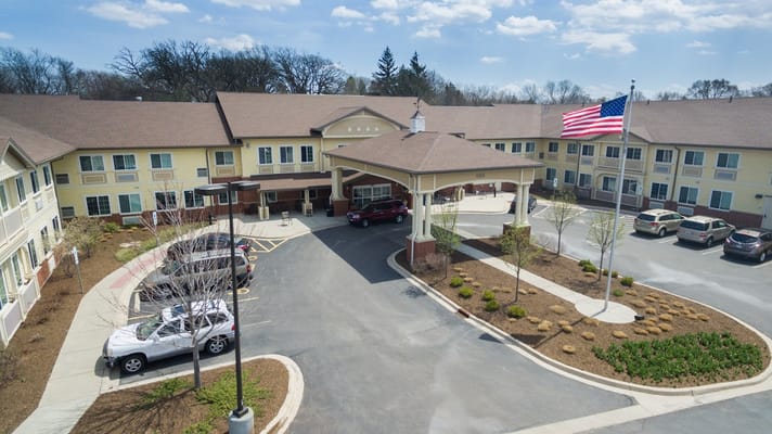 Aerial view of the entrance to Three Oaks Assisted Living with a flag and parked cars