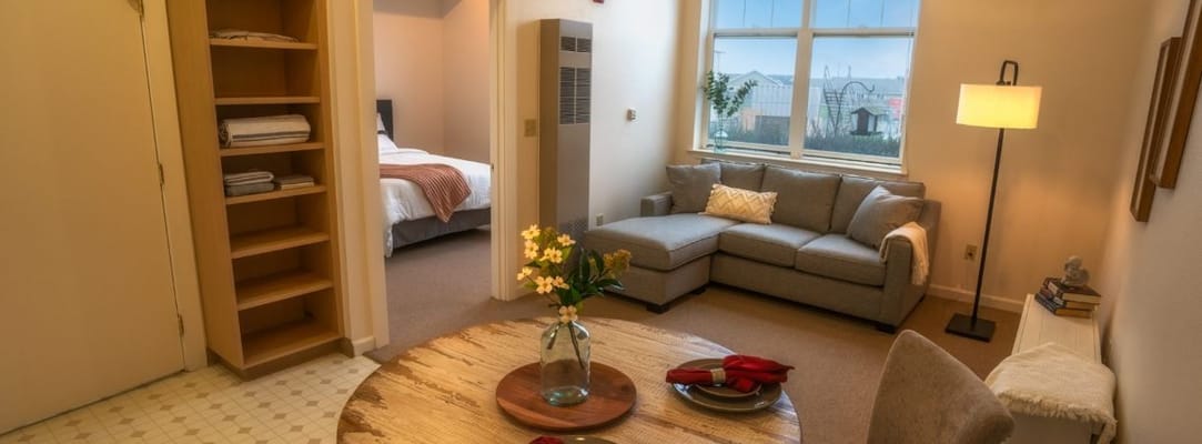 A cozy living area featuring a sofa, dining table, and access to a bedroom.