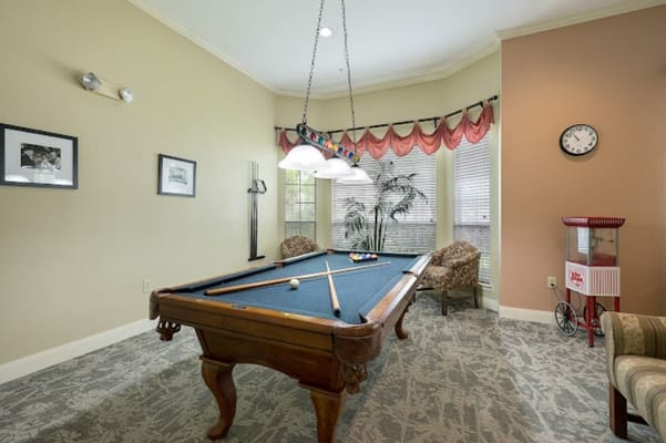 A billiards table in a cozy lounge area with soft lighting and decorative accents.