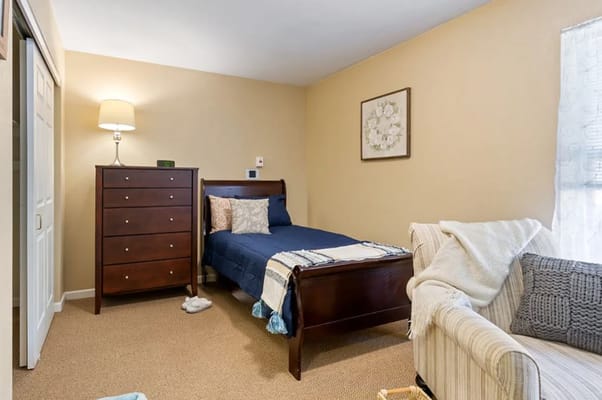 A cozy bedroom with a bed, dresser, and light-colored walls