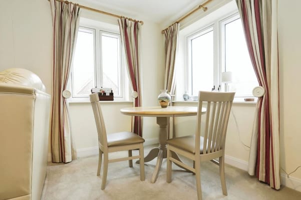 A small dining area with a round table and two chairs by a window.